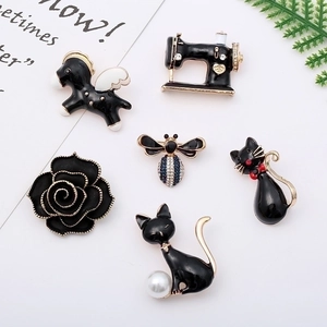 Set of six cute black enamel animal and plant brooches with gold plating on a white background