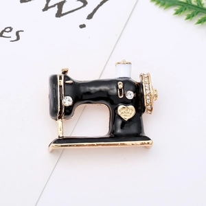 Detailed macro view of a vintage sewing machine brooch with black enamel and gold crown