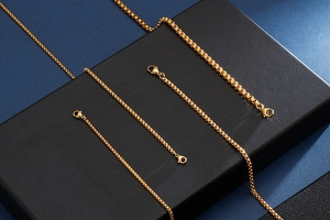 Detailed macro shot of a polished golden stainless steel box chain with lobster clasp