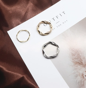 Close-up of gold and silver irregular twisted wave rings on a white aesthetic card