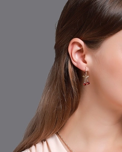 Vue détaillée de boucles d'oreilles cerise avec pierres rouges et dorures
