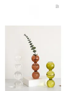 Gros plan de vases à bulles à trois niveaux en verre clair, ambre et vert pour décor