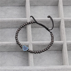 Detailed close-up of heart charm with blue zircon on beaded bracelet in a velvet box