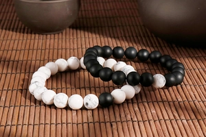 Detailed texture of 8mm matte black stone and white turquoise couple bracelets on bamboo