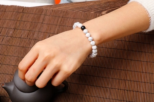 Detail of 8mm white turquoise and black marble bead bracelet on wrist with tea set background