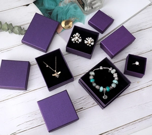 Deep purple jewelry gift boxes with black velvet lining in various sizes on white wood