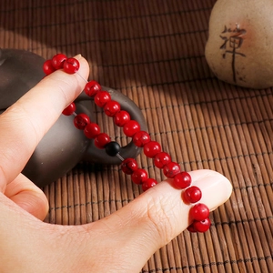Retro red beaded bracelet with black veins and elastic cord on a Zen bamboo mat