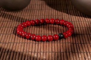 Macro view of red textured agate beads and black matte bead on a bamboo mat base
