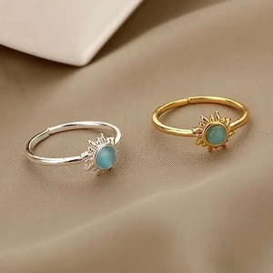 Adjustable sun-shaped opal rings in gold and silver finish on beige fabric