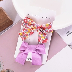 Detail of floral and purple handmade bow hair clips on display card for girls