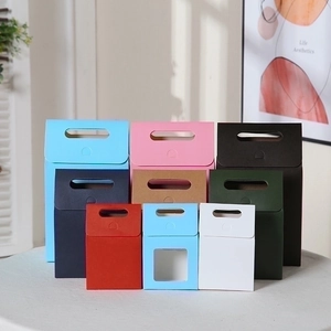 Minimalist multi-color gift boxes with handles and window in a warm home setting