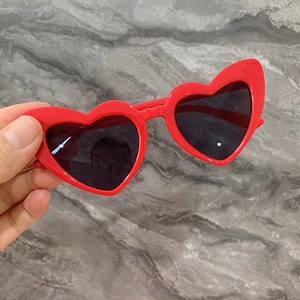 Détail de lunettes de soleil coeur rouges pour enfants avec verres foncés et monture en plastique