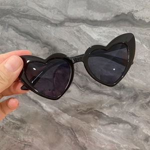 Vue détaillée de lunettes de soleil en forme de cœur avec monture noire et verres gris