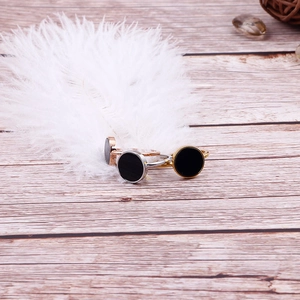Elegant 18k gold and silver plated circular rings with black centers on a white feather