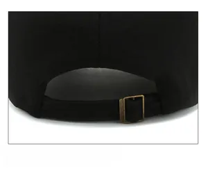 Detail of black cotton baseball cap with adjustable strap and brass metal buckle