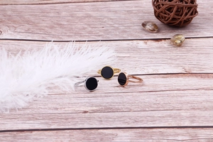 Three minimalist stainless steel rings with round black inlay on wooden surface