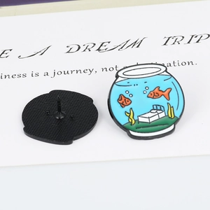 Detail of fish tank enamel pin showing orange goldfish and back needle fastening