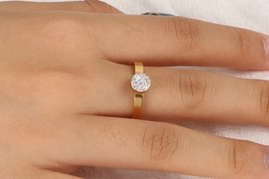 Gros plan d'une bague dorée incrustée de diamants portée au doigt avec un serti pavé minimaliste