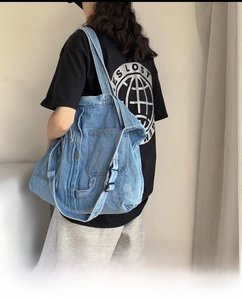 Detail of adjustable strap and metal snap button on blue washed denim crossbody bag