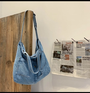 Close-up of a blue denim tote bag hanging on a rustic wooden board with vintage decor
