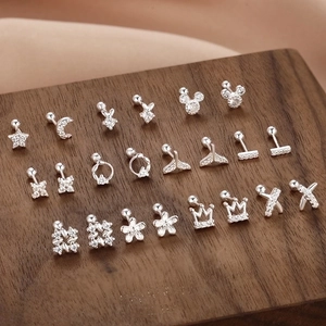 Macro view of 999 silver heart and star stud earrings with cubic zirconia on wood