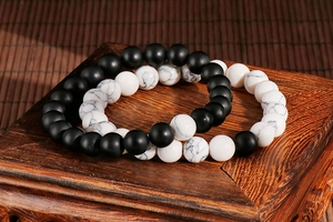 Detail of white turquoise and black matte stone beaded bracelets on vintage wooden stand