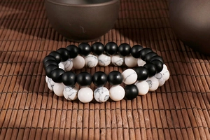 Detailed view of matte black and white marble bead elastic bracelets on a bamboo mat