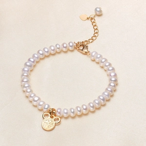 Elegantes Süßwasserperlenarmband mit goldenem Fu-Anhänger auf beigem Seidenstoff