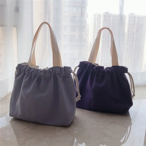 Detail of drawstring canvas tote bags in light and dark purple with beige handles