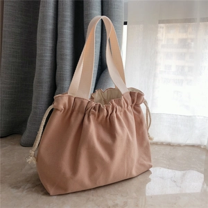 Detail of canvas drawstring handbag in soft apricot with thick cotton web handles