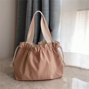 Detail of soft pink drawstring canvas handbag with durable cream-white handles