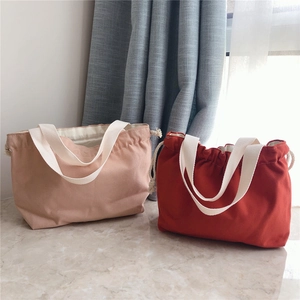 Detail of pink and orange canvas tote bags with drawstring design and white handles