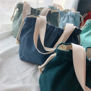 Detailed arrangement of colorful canvas drawstring tote bags with woven handles