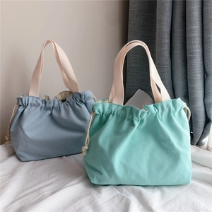Detail of light green and grey blue canvas drawstring bags with off-white handles