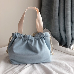 Detail of light blue drawstring canvas tote bag with thick off-white woven handles