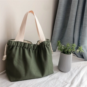 Close-up of dark green canvas drawstring handbag with cream-white cotton straps