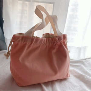Close-up of pink canvas tote bag with drawstring closure and cream-colored handles