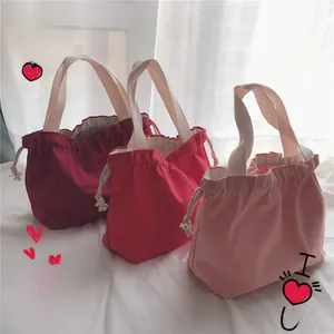 Detail of burgundy and pink drawstring canvas tote bags with thick woven handles