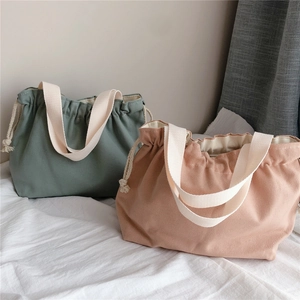 Detailed close-up of thick drawstring canvas handbags in sage green and soft pink colors