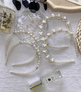 Close-up of pearl and rhinestone hairbands with heart gemstone details on white fabric
