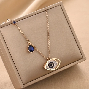 Golden Evil Eye necklace with blue teardrop crystal on premium jewelry display case