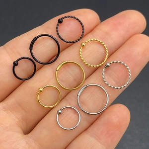 Detailed set of silver, gold, and black nose hoops with twisted designs on human hand