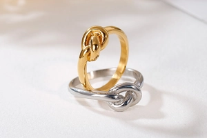 Macro shot of minimalist gold and silver knot rings with polished finish on white surface