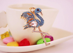 Close-up of gold flamingo keychain with blue rhinestones leaning on white cup