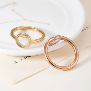 Elegant gold and rose gold heart rings with floating particles on a ceramic tray