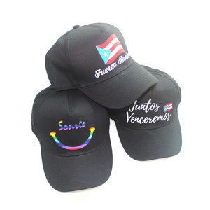 Three custom black baseball caps with flag graphics and Spanish motivational phrases