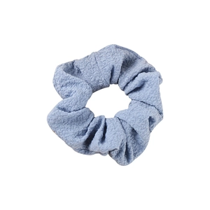 Minimalist light blue seersucker scrunchie with soft pleated texture on white background