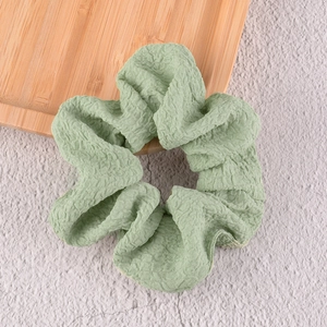 Détail d'un chouchou vert clair en seersucker avec texture plissée sur plateau