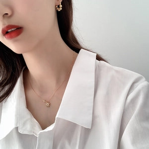 Close-up of starburst pendant necklace and stud earrings set in gold finish