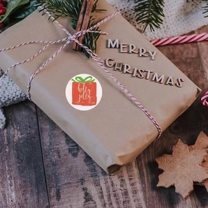 Holly Jolly Christmas labels on gift packaging with festive decor on dark wood